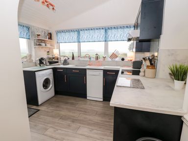 A kitchen with a washing machine dishwasher microwave kettle and countertop at St Cuthberts Cottage Beal near Holy Island