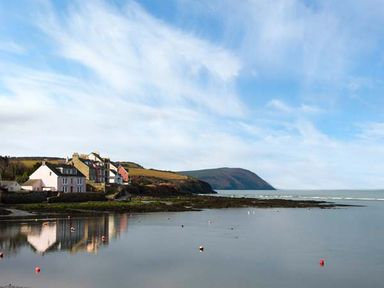 A coastal village with houses near a calm sea and hills in the background at Rose Cottage in St Dogmaels near Cardigan