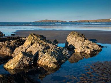 A rocky shoreline with tide pools and distant islands at Rose Cottage in St Dogmaels near Cardigan