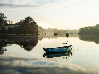 A small boat floating on calm water with trees and other boats in the background at Rose Cottage in St Dogmaels near Cardigan