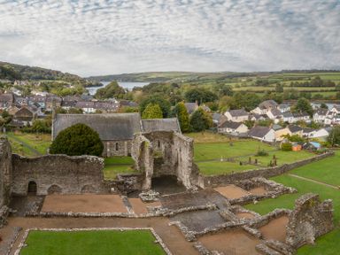 A landscape view of a village with ancient stone ruins and a church near a river at Rose Cottage in St Dogmaels near Cardigan