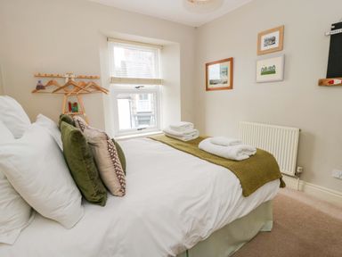 A bedroom with a bed and wall art at Rose Cottage St Dogmaels near Cardigan