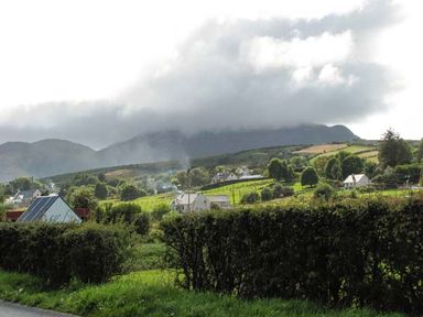 A rural landscape with houses fields trees and hills under a cloudy sky at The Beach House Apartment in Buncrana County Donegal