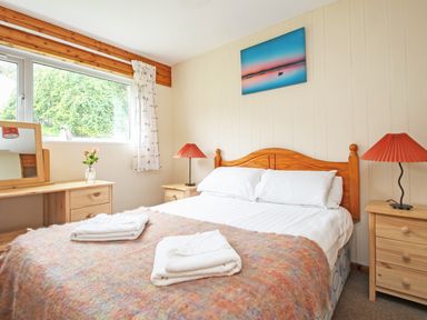 A bedroom with a double bed two bedside tables with lamps a dressing table with a mirror and a window at 4 Manorcombe Honicombe Manor near Gunnislake