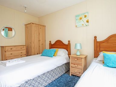 A bedroom with two single beds a wooden wardrobe chest of drawers and a bedside table with a lamp at 4 Manorcombe Honicombe Manor near Gunnislake