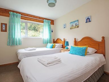 A bedroom with two single beds with wooden headboards and blue and yellow pillows at 4 Manorcombe in Honicombe Manor near Gunnislake