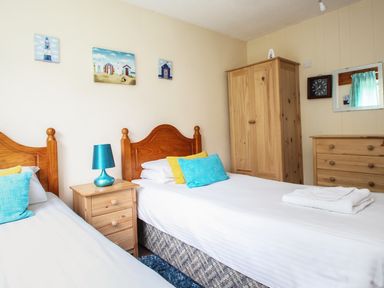 A bedroom with two single beds a bedside table with a lamp a wooden wardrobe and a dresser with a mirror at 4 Manorcombe in Honicombe Manor near Gunnislake