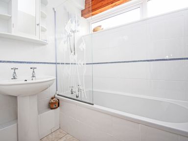 A bathroom with a pedestal sink a bathtub with glass shower screen and a small window at 4 Manorcombe Honicombe Manor near Gunnislake