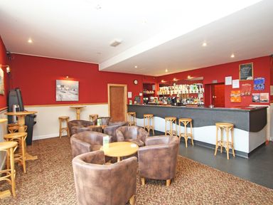 A bar area with stools armchairs tables and a counter with drinks at 4 Manorcombe Honicombe Manor near Gunnislake