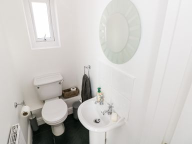 A small bathroom with a toilet sink mirror and window at 1 Atlantic Haven in Llangennith