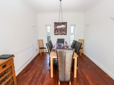 A dining room with wooden table and leather chairs on wooden floor at 1 Atlantic Haven in Llangennith