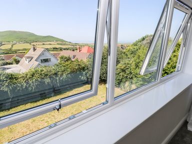 A view of countryside and houses through open white framed windows at 1 Atlantic Haven in Llangennith
