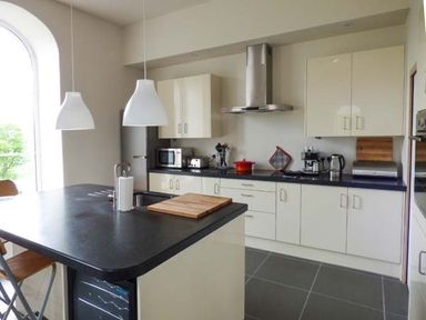 A kitchen with a black island countertop white cabinets and various appliances at Capel Dinorwig in Llanberis