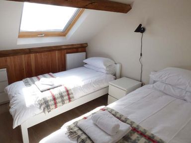 A bedroom with two single beds bedside table and skylight window at Capel Dinorwig in Llanberis