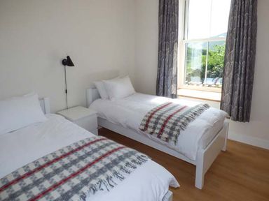 A bedroom with two single beds a nightstand and a window at Capel Dinorwig in Llanberis