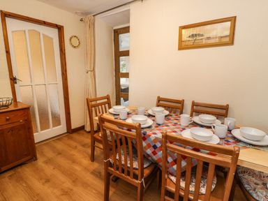 A dining room with a wooden table set for six and wooden chairs at Bwthyn Fedwr Gog in Maerdy near Bala