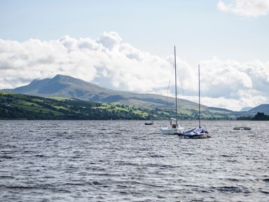 A lake with sailboats and hills in the background at Bwthyn Fed'wr Gog in Maerdy near Bala