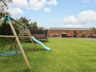 An outdoor area with a swing set and trampoline at Stable Cottage, Bolton Low Houses