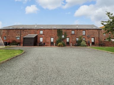 An outdoor area with a brick building and gravel path at Stable Cottage in Bolton Low Houses