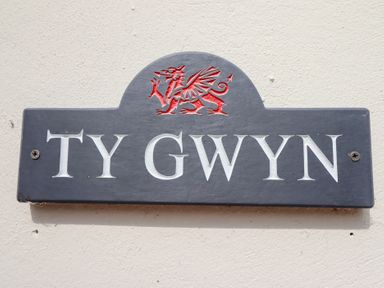 A nameplate with TY GWYN and a dragon crest at Ty Gwyn in Llangwm near Bala