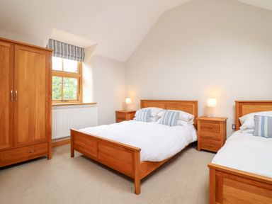 A bedroom with two beds and a wardrobe at Ty Gwyn in Llangwm near Bala