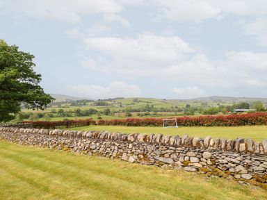 An outdoor photo of a landscape with a stone wall and a goal post at Ty Gwyn in Llangwm near Bala