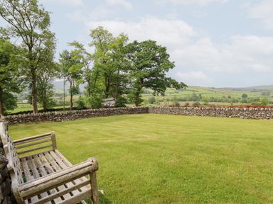 A garden with grass and trees at Ty Gwyn in Llangwm near Bala