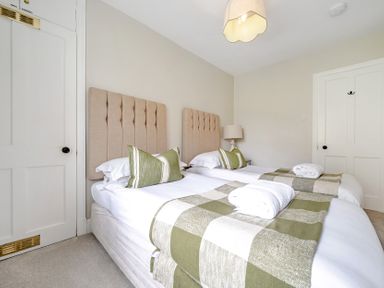 A bedroom with two beds and a bedside table at Dove Cottage at the Graythwaite Estate