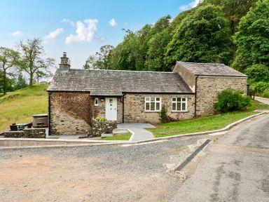 A stone house with a pathway and trees at Dove Cottage at the Graythwaite Estate near Hawkshead
