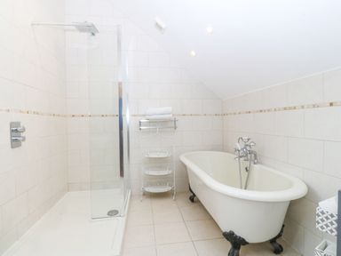 A bathroom with a clawfoot bathtub shower enclosure and a towel rack at Nant-yr-Rhedyn in Red Wharf Bay