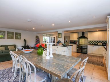 A kitchen with a dining area and appliances at Nant-yr-Rhedyn in Red Wharf Bay