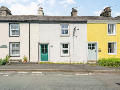 A row of three adjoining cottages with different colored doors and walls on a roadside at No 7 Spark Bridge near Ulverston