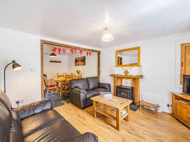 A living room with leather sofas and a wood coffee table next to a dining area at No 7 Spark Bridge near Ulverston