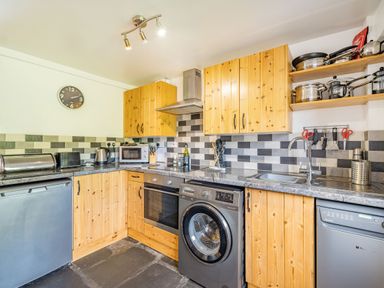A kitchen with wooden cabinets countertop appliances and tiled backsplash at No 7 Spark Bridge near Ulverston