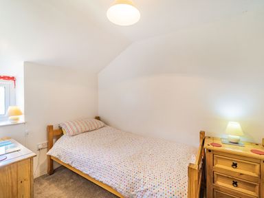 A bedroom with a single bed a wooden chest of drawers and two lamps at No 7 Spark Bridge near Ulverston