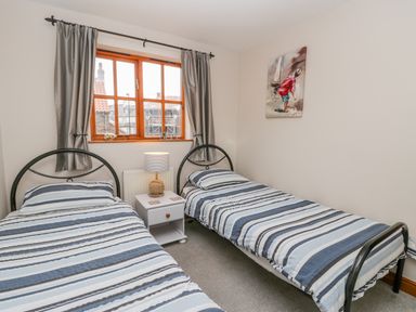 A bedroom with two single beds with striped bedding and a lamp on a nightstand between the beds at Little Venice in Whitby