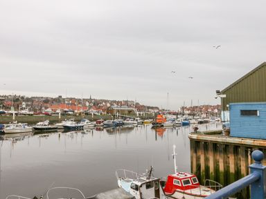 A harbor view with multiple docked boats and a town with houses in the background at Little Venice in Whitby