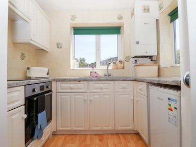 A kitchen with white cabinets countertop oven toaster and windows at Moorside Horrabridge near Tavistock