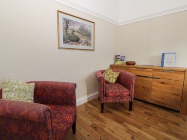 A corner with two patterned armchairs a wooden sideboard a framed painting on the wall at Seascape in Bridlington