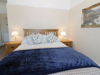 A bedroom with a wooden bed and two bedside tables with lamps at Seascape in Bridlington