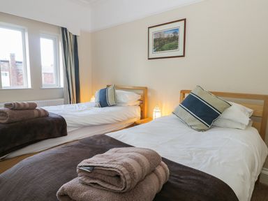 A bedroom with two single beds each with pillows towels and blankets at Seascape in Bridlington