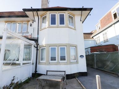 A white house exterior with bay windows and metal table and bench on the patio at Seascape in Bridlington