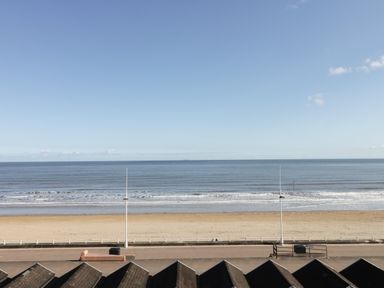 A beach with sand and waves beside a paved promenade with street lamps at Seascape in Bridlington