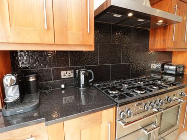 A kitchen countertop with a coffee machine kettle toaster and a gas stove with oven at Bryn Derw Holiday Cottage Eglwysbach near Llanrwst and Conwy