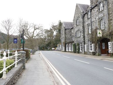 A street with a stone building labeled Royal Oak Hotel on the right and a sidewalk with signs on the left at Bryn Derw Holiday Cottage Eglwysbach near Llanrwst and Conwy