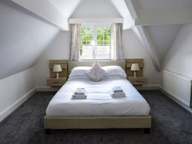 A bedroom with a bed towels and bedside lamps under a window at The Nook in Bowness-On-Windermere