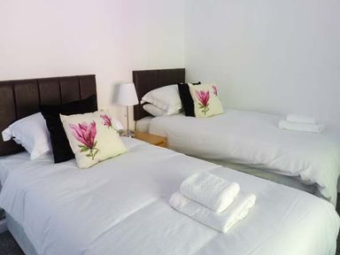 A bedroom with two single beds with white bedding and floral pillows at The Nook in Bowness-On-Windermere