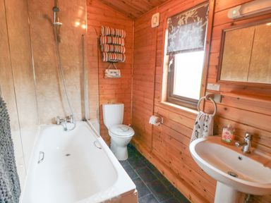 A bathroom with a bathtub shower toilet sink and wooden walls at Hawthorne Lodge in Liverton near Danby