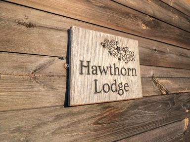 A wooden sign with the text Hawthorn Lodge mounted on a wooden wall at Hawthorne Lodge in Liverton near Danby