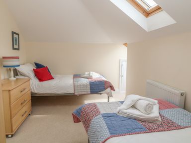 A bedroom with two single beds a wooden chest of drawers and a skylight window at Atlantic Reach in Widemouth Bay